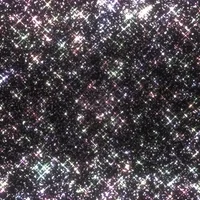 A gif of sparkles that appear to be moving out of a dark background towards the viewer.